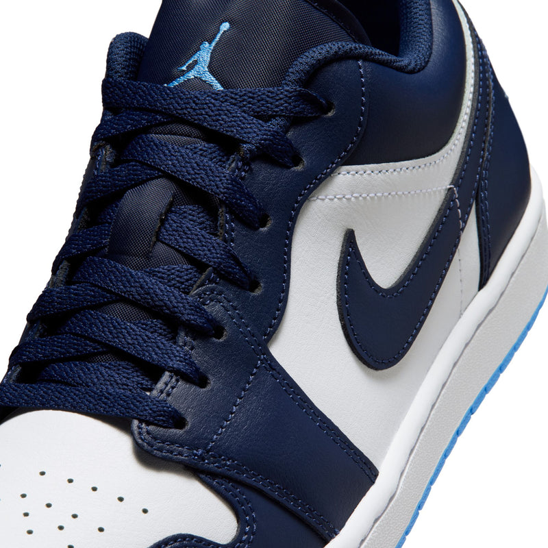 Close-up of men's lace-up sneakers, navy leather with white panel and blue Swoosh.