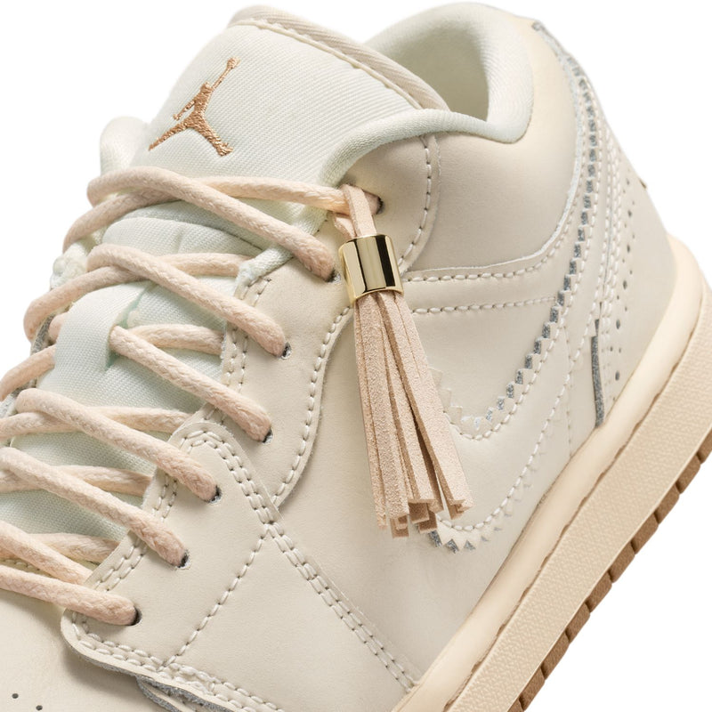 Close-up of women’s cream sneaker upper with lace-up ties and tassel trim.