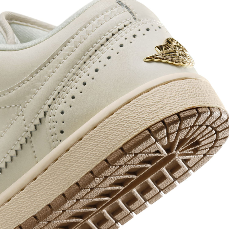 Close-up of women’s cream sneaker side with gold emblem and textured outsole.