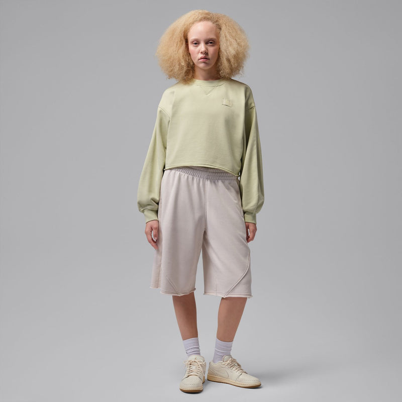 Women’s cream low-top sneakers on a model wearing cropped pants and light socks.