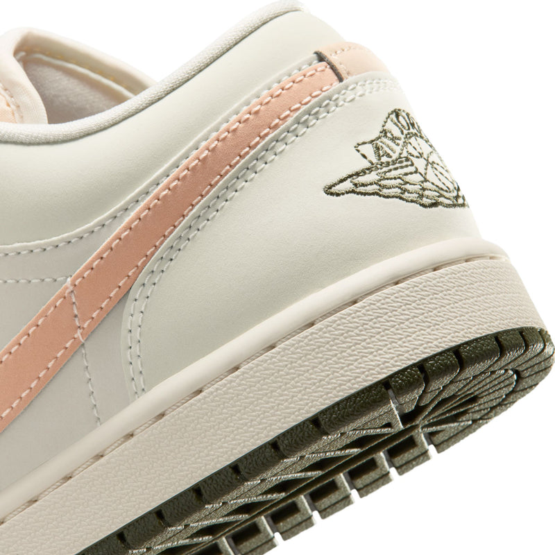 Close-up of women's low-top sneaker side with pink stripe, wing logo, and textured sole