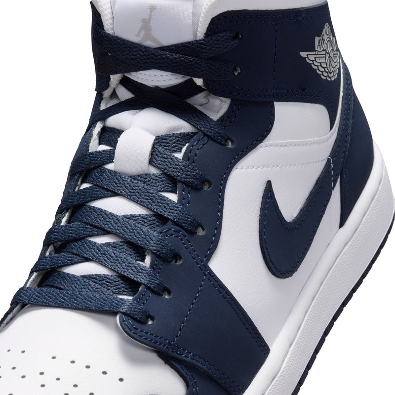 Close-up of navy and white mid-top sneaker with laces and wing logo on collar