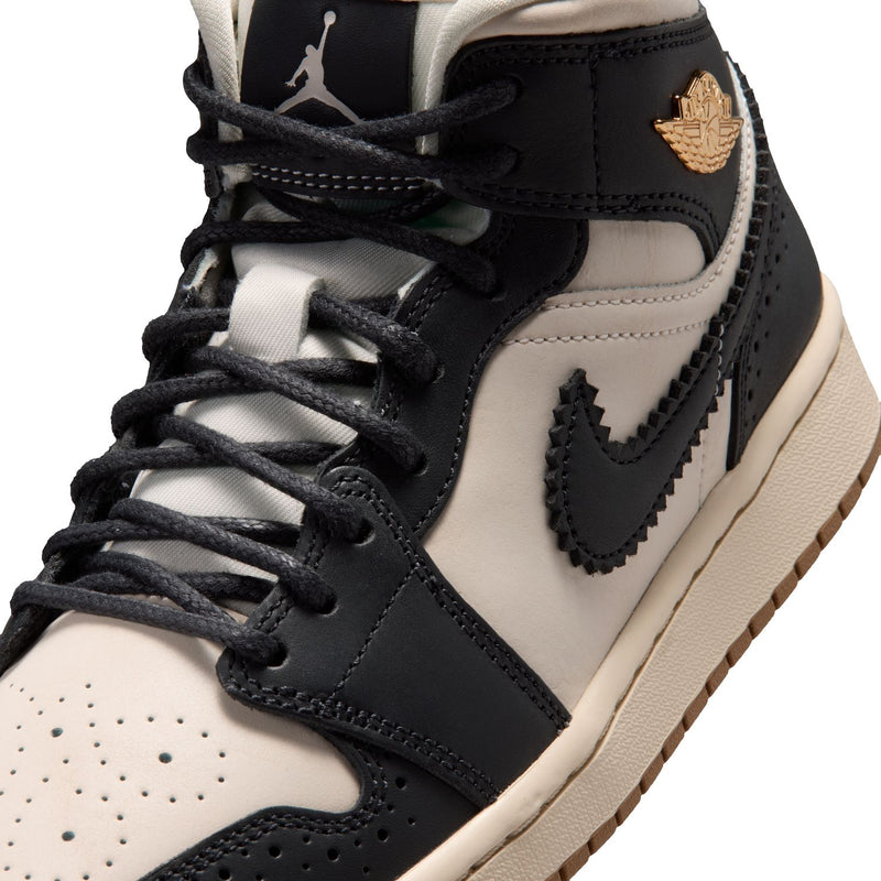 Close-up of women’s mid-top sneaker upper with black laces and wing-style emblem