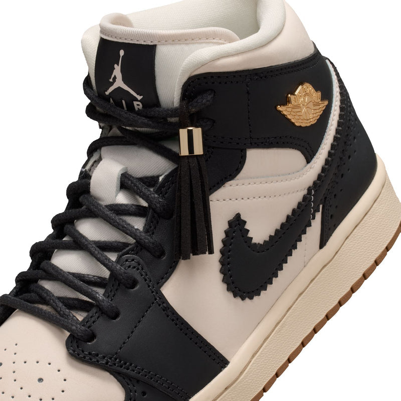 Close-up of women’s mid-top sneakers with black laces and metallic lace toggle detail