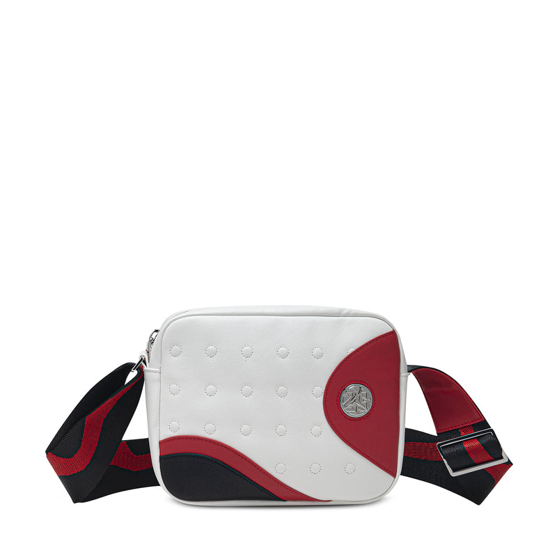 White leather-look crossbody bag with red side panel, round logo, and plaid strap