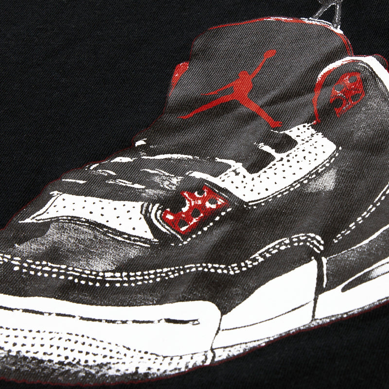 Black T-shirt close-up of sneaker graphic with red Jordan logo and white laces