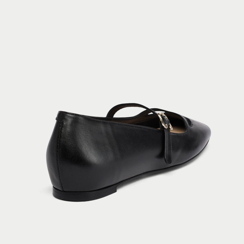 Black leather flat shoe with a gold buckle on a white background
