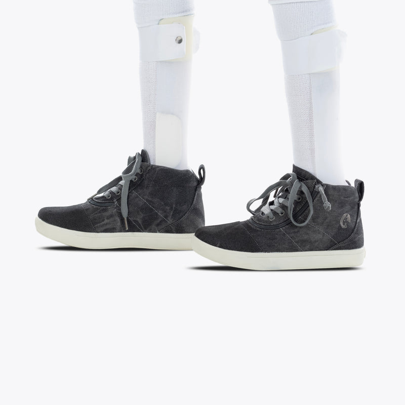 A person wearing Black Acid Wash BILLY D|R II Short Wrap High shoes from BILLY Footwear and white orthotic leg braces, shown from the side against a white background.