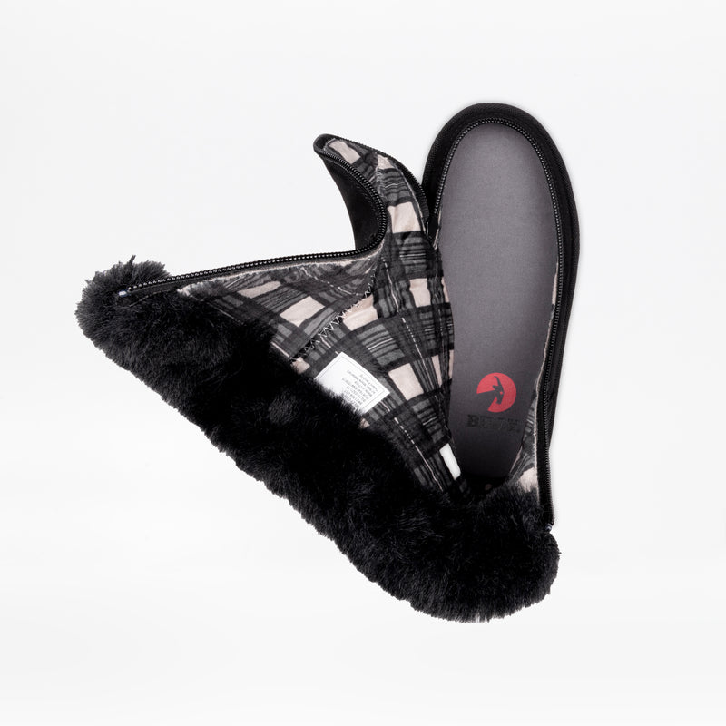 The Black BILLY Cozy II slippers by BILLY Footwear feature a plaid fabric exterior, soft black fur lining, and a partially open zipper showing the flannel-lined interior. The shoes are displayed overlapping each other on a white background.