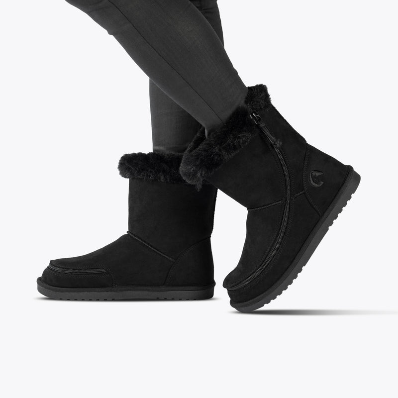Wearing black BILLY Cozy II boots by BILLY Footwear with dark skinny pants, this person stands against a plain white background.