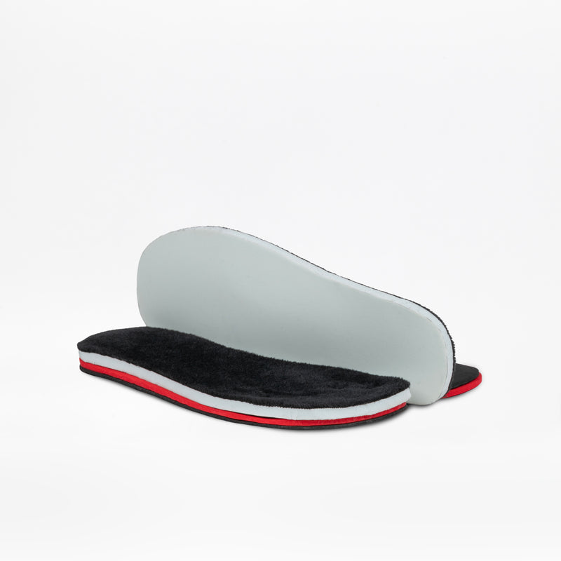 Two shoe insoles from the Black BILLY Ice Boot by BILLY Footwear have black plush tops, white midsoles, and red accents. One insole lies flat, while the other shows its plain light gray underside propped behind it.