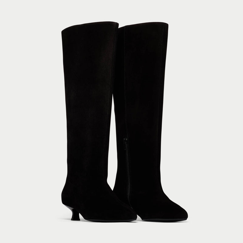 Black knee-high boots on a light gray background