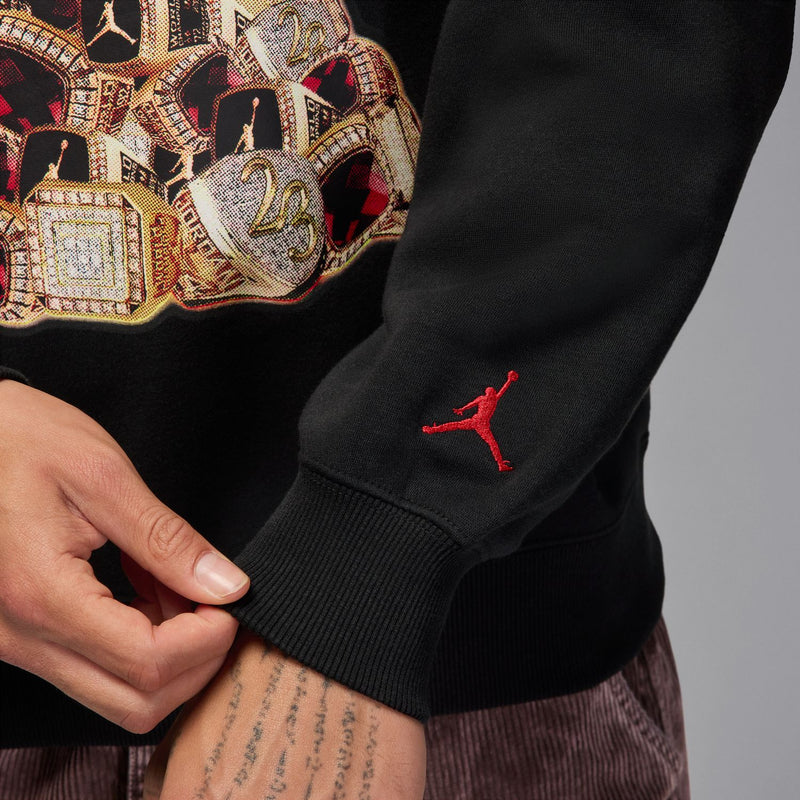 Black crewneck sweatshirt sleeve with red Jumpman logo near the cuff