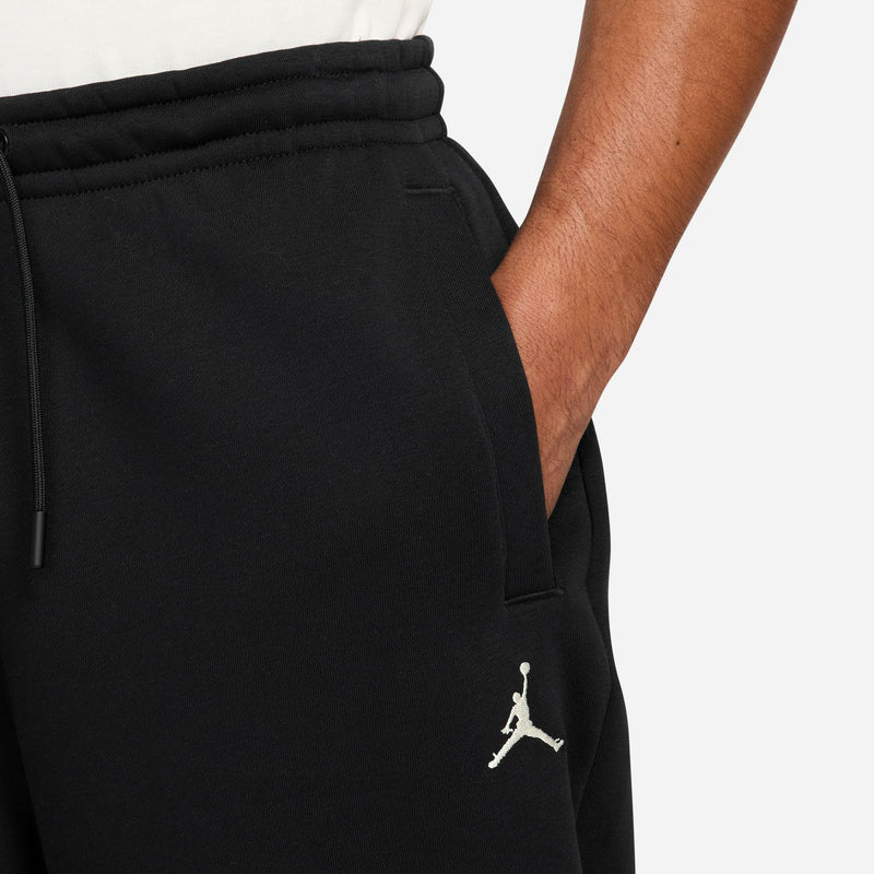 Black jogger pants detail: elastic waistband, drawcord, and Jumpman-style side logo