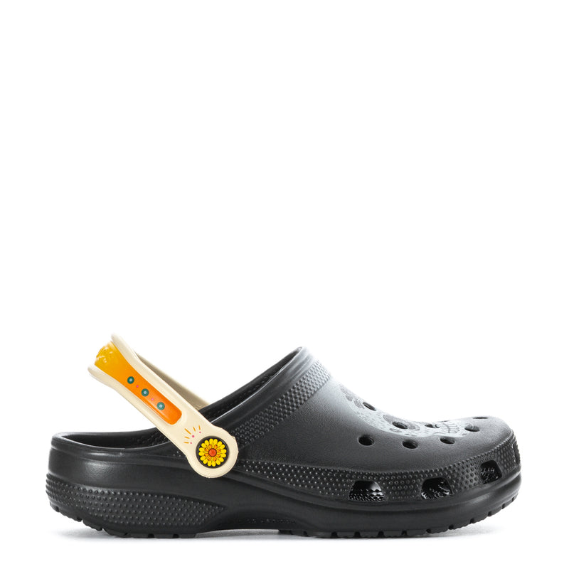 Black clog with perforations and round flower emblem on side strap