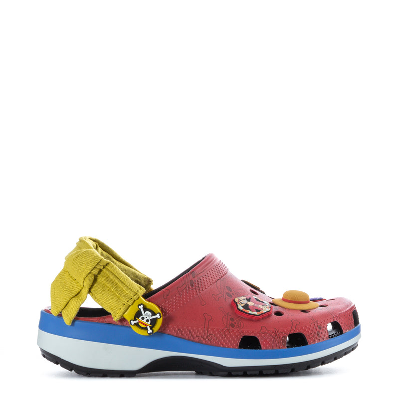 Youth clog in pink/red with blue sole, yellow strap, and pirate-themed emblem on side