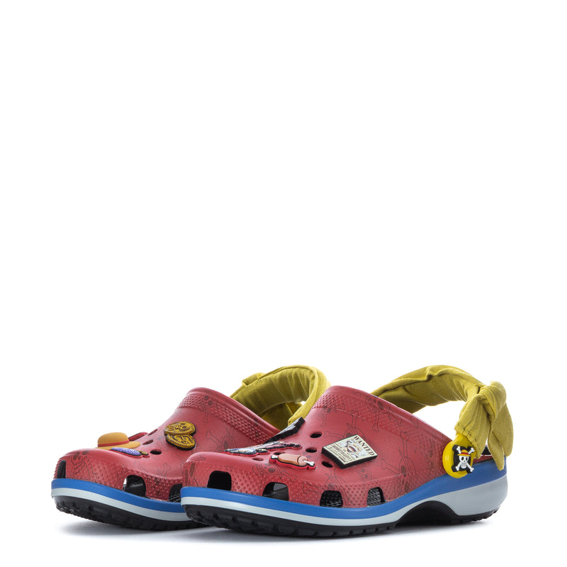 Pair of youth clogs in pink/red with blue soles and yellow straps, showing multiple pirate graphics