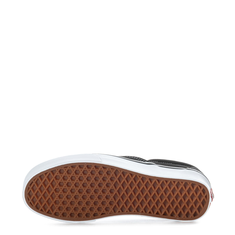 Black slip-on sneakers showing textured gum outsole with white edge trim