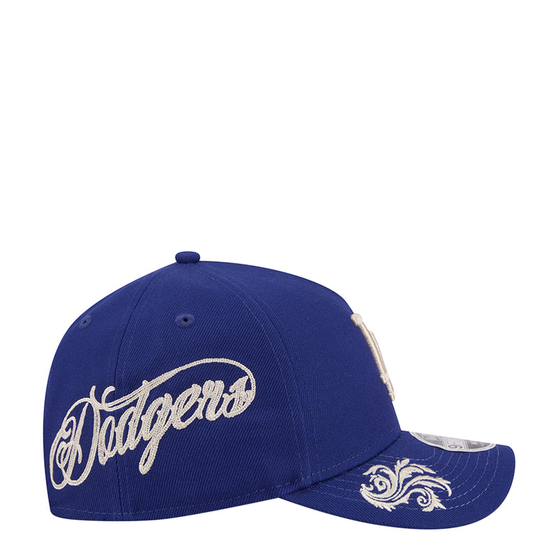 Blue baseball cap with large white Dodgers wordmark and ornate side panel embroidery