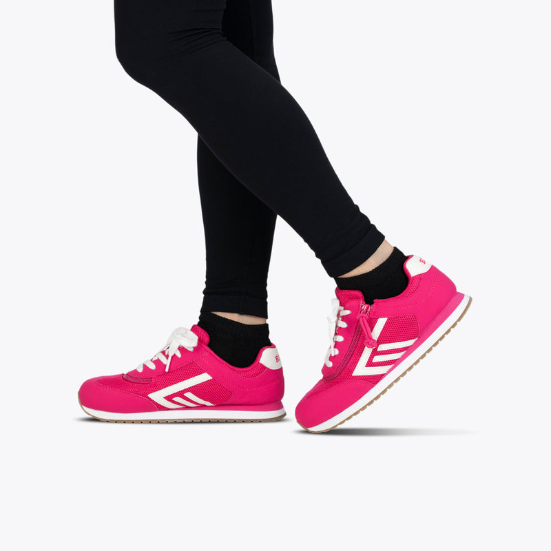 A person in black leggings stands on tiptoe against a white background, wearing Fuchsia BILLY Retro Jogger sneakers by BILLY Footwear with white soles and accents.