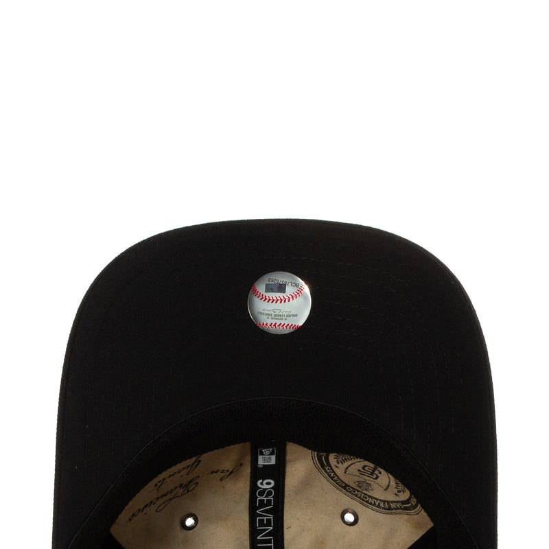 Black baseball cap interior with stitched button and baseball graphic on crown.