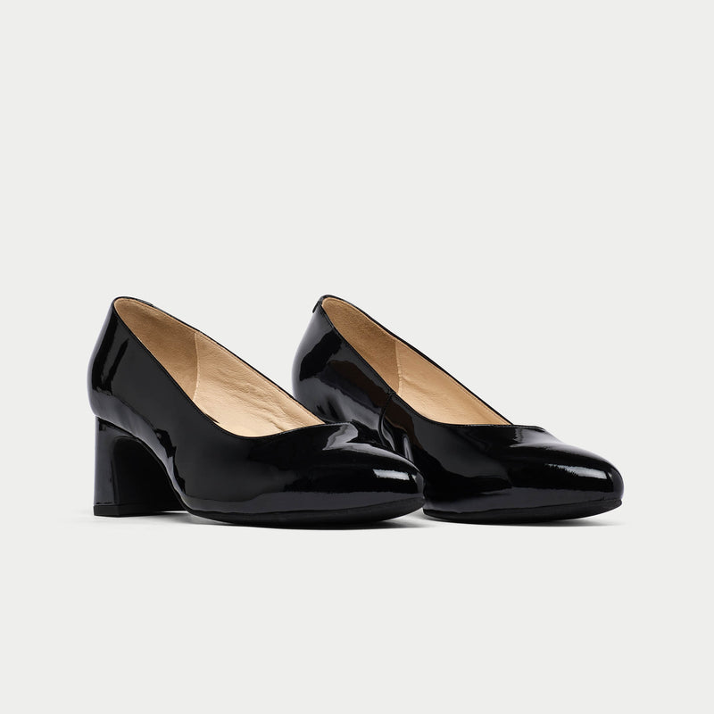 Pair of black patent leather high heels on a light gray background