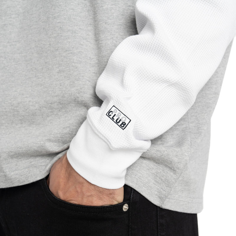 White long-sleeve cuff with logo patch under heather gray shirt