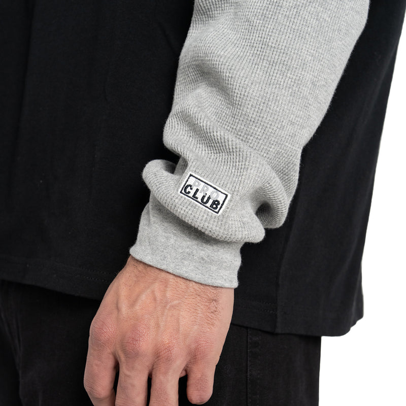 Ribbed heather grey cuffs with small logo patch on black thermal shirt