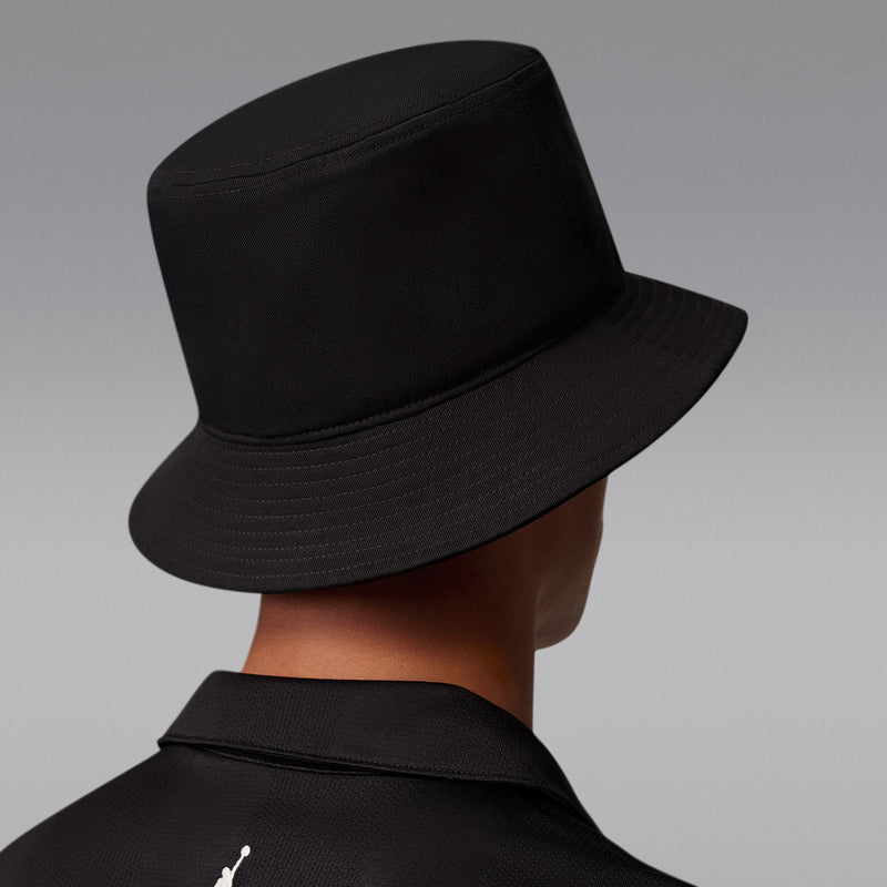 Black bucket hat with Jumpman logo near side seam, model wearing it.