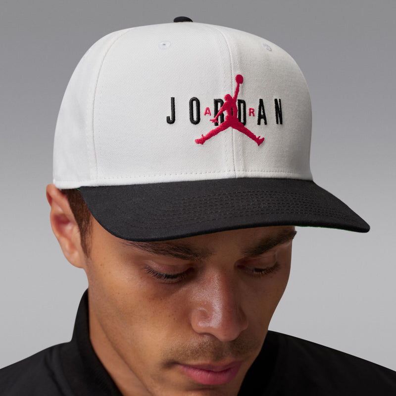 White cap with red Jumpman and black Jordan letters; dark curved bill