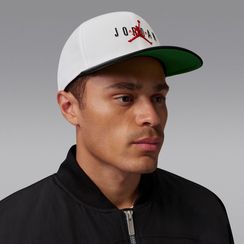 White snapback cap with red Jumpman and black Jordan letters; green underside