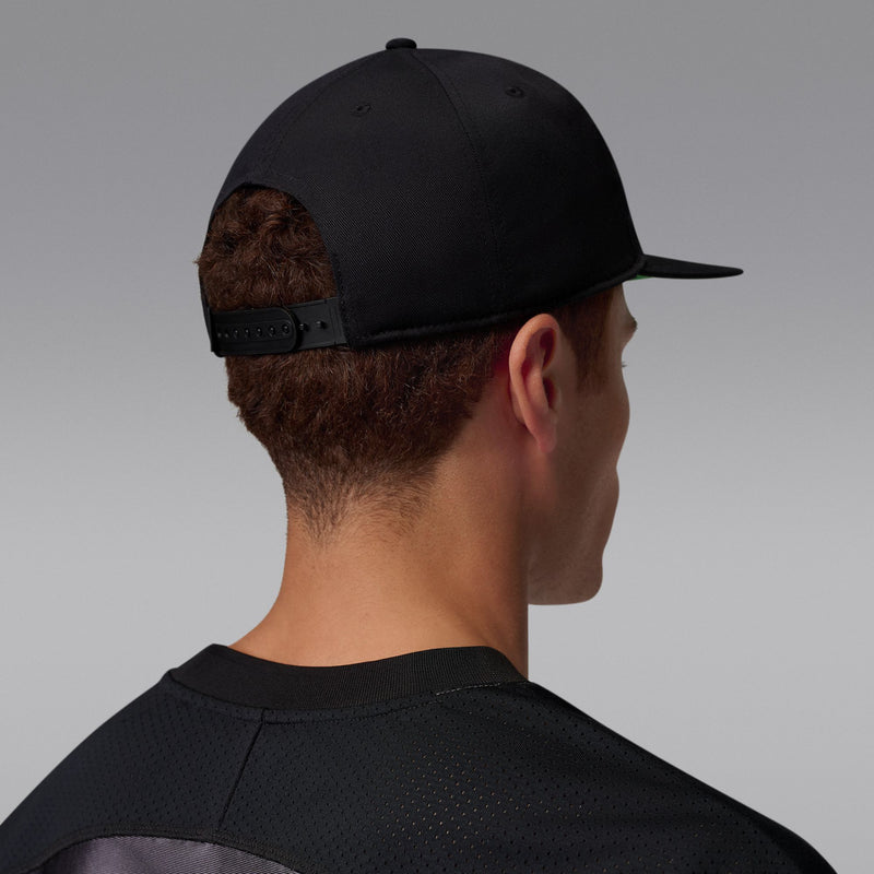 Black snapback cap, side view with adjustable strap and no front logo