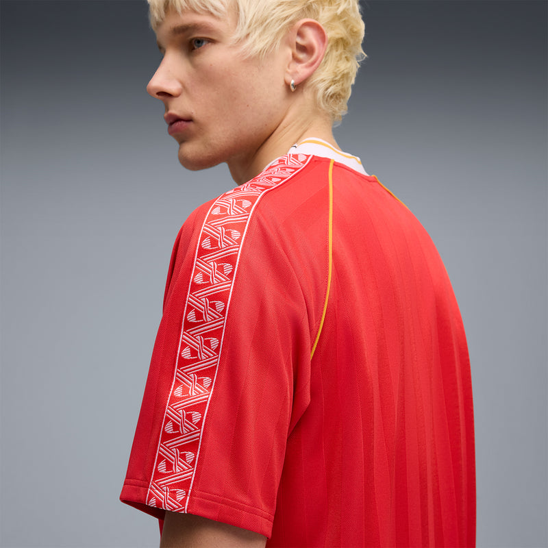 Red soccer jersey side view with patterned sleeve trim and yellow piping