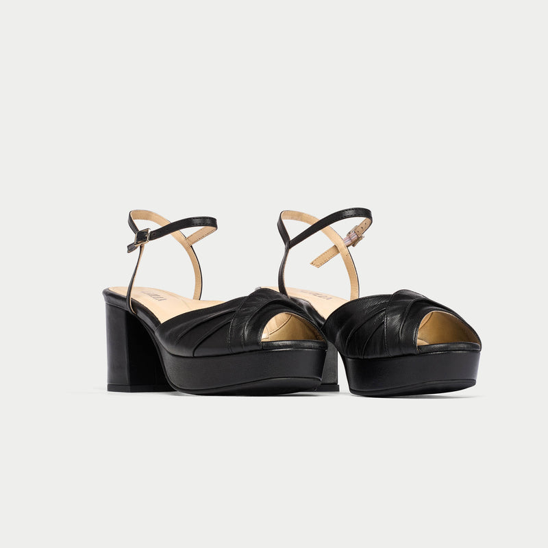Black platform sandals with thin straps on a light gray background