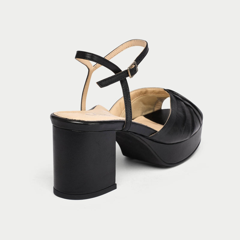Black platform sandal with a thin strap on a light gray background