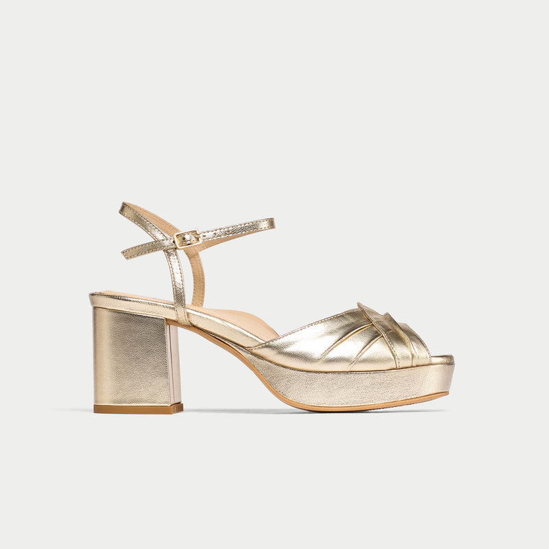 Gold high-heeled sandal on a light gray background