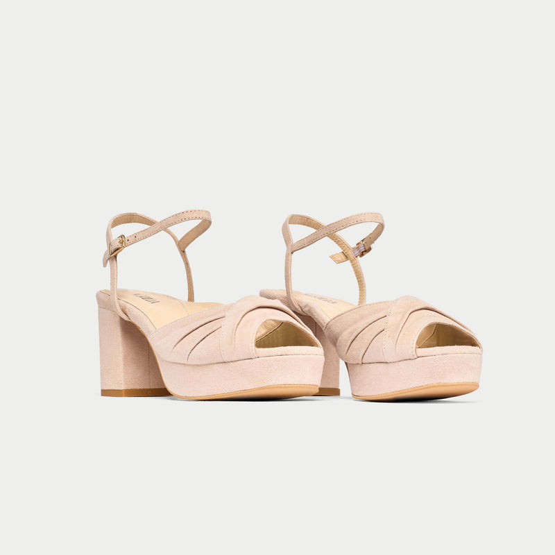 Pair of beige high-heeled sandals on a light gray background