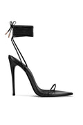 FEMME LA Luce Minimale in black — side profile of black stiletto sandal with thin toe strap and multi-wrap lace-up ankle cuff tied in a bow with gold aglets