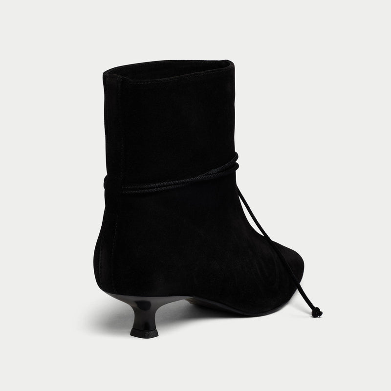 Black ankle boot with a thin heel on a light gray background