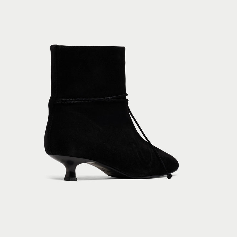 Black ankle boot with a kitten heel on a light gray background