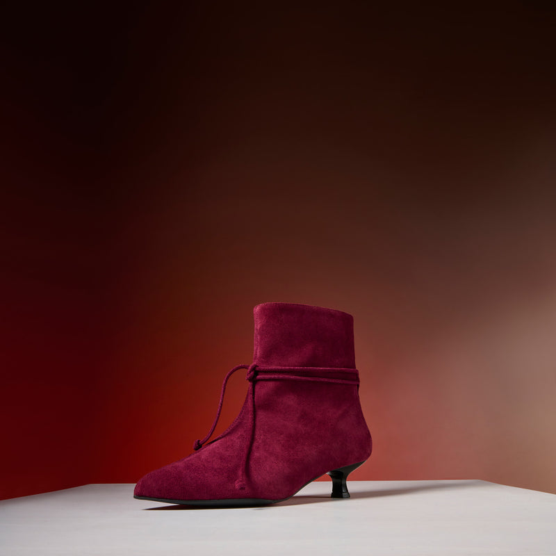 Maroon suede shoe on a gradient background