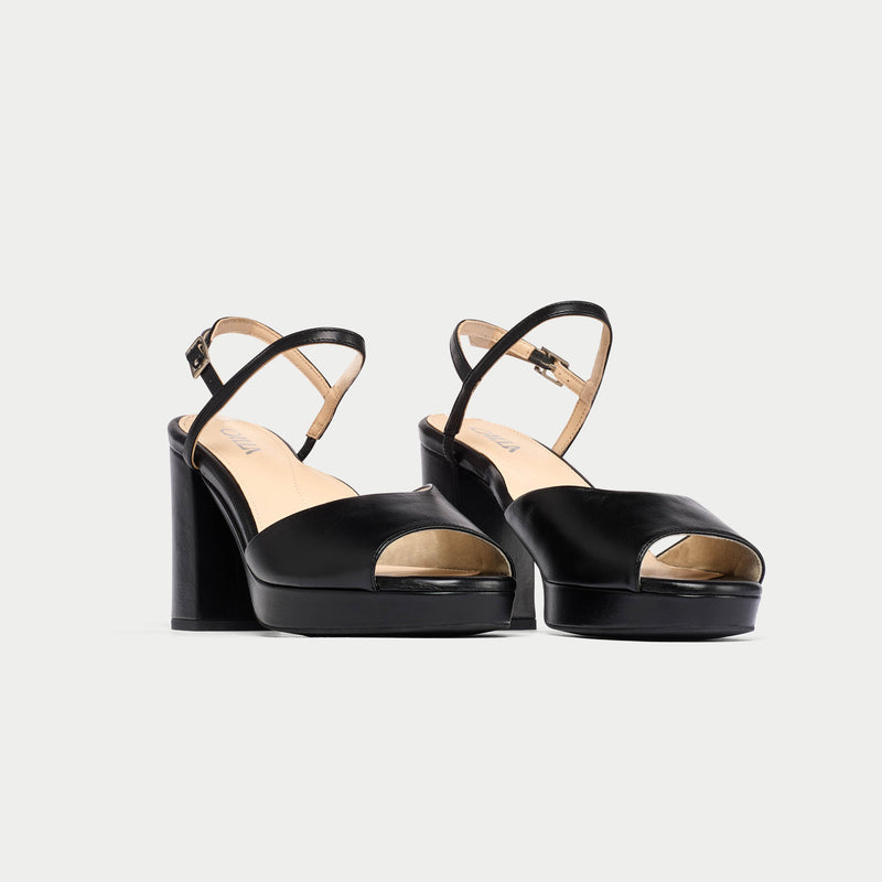 Black high-heeled sandals on a light gray background