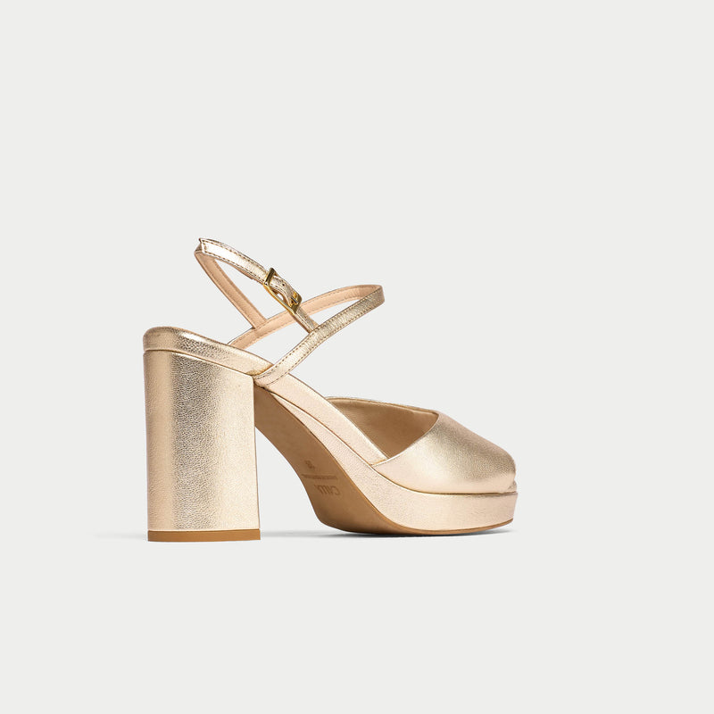 Gold high-heeled shoe on a light gray background
