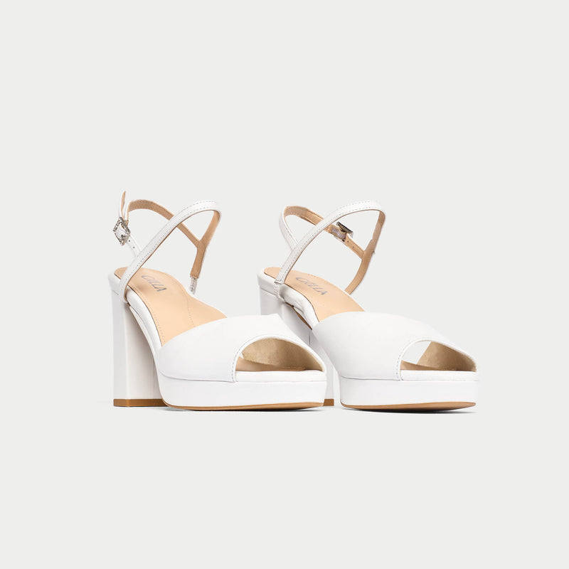 White high-heeled sandals with beige soles on a white background