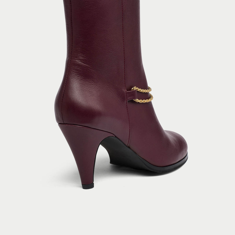 Maya cherry leather boot with gold chain detail on a white background heel close-up