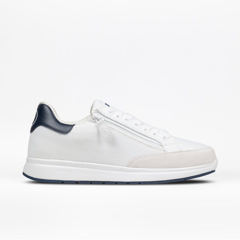 The Men's White/Navy BILLY Comfort Court by BILLY Footwear is a minimalist, low-cut white sneaker with a blue heel tab, white laces, and a white sole, shown in side profile on a white background.