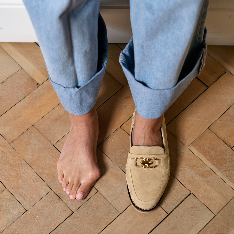 Person wearing beige loafers on a wooden floor