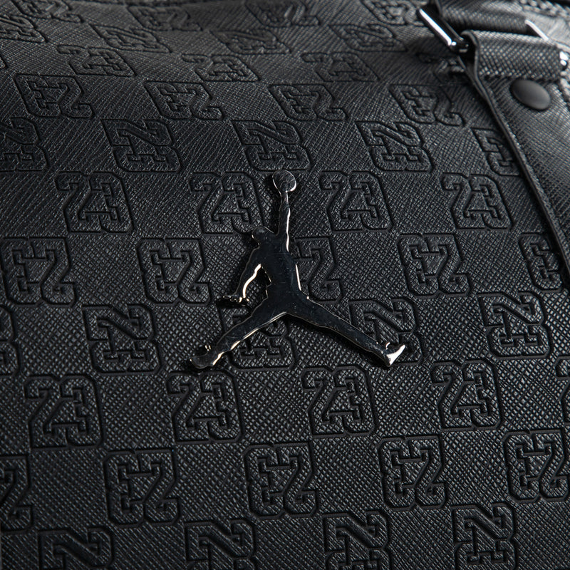 Black monogram duffel bag close-up of embossed logo pattern