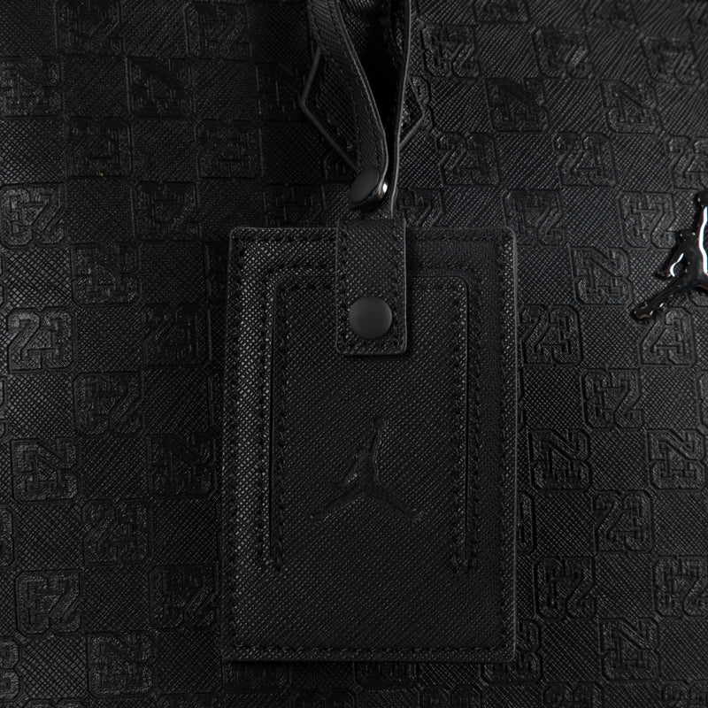 Black monogram tote bag with hanging leather ID tag and zipper detail