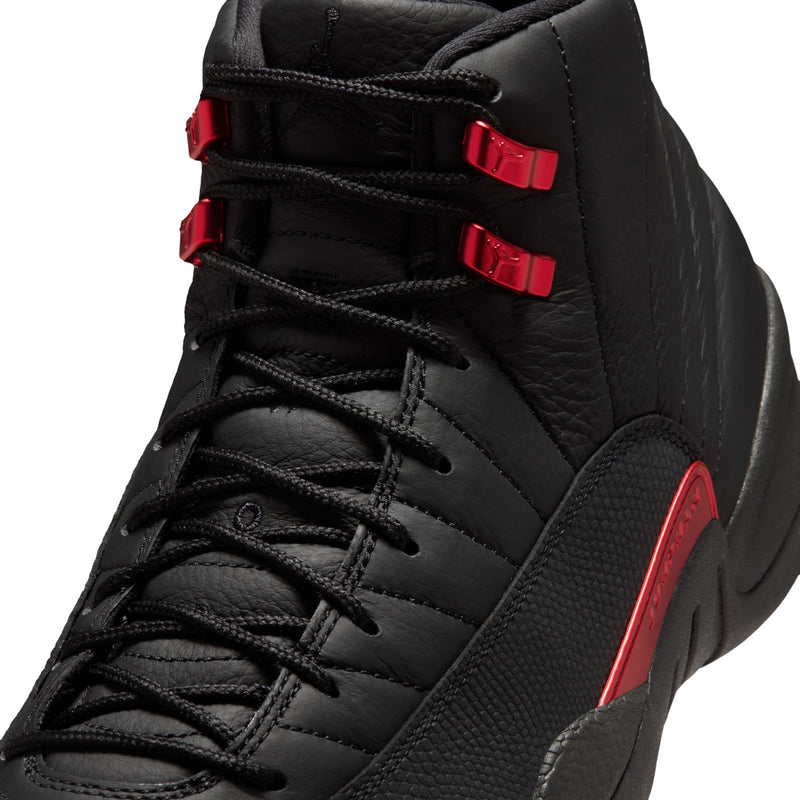 Men's black high-top sneaker close-up with red lace straps and textured leather